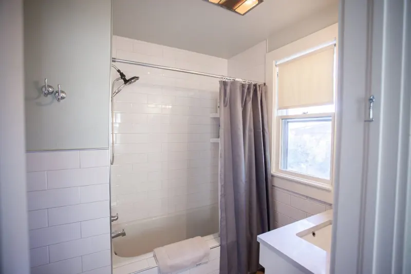 Bathroom with a white-tiled tub and shower