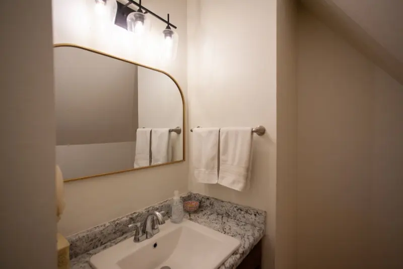 Bathroom vanity with a granite counter and an arched mirror