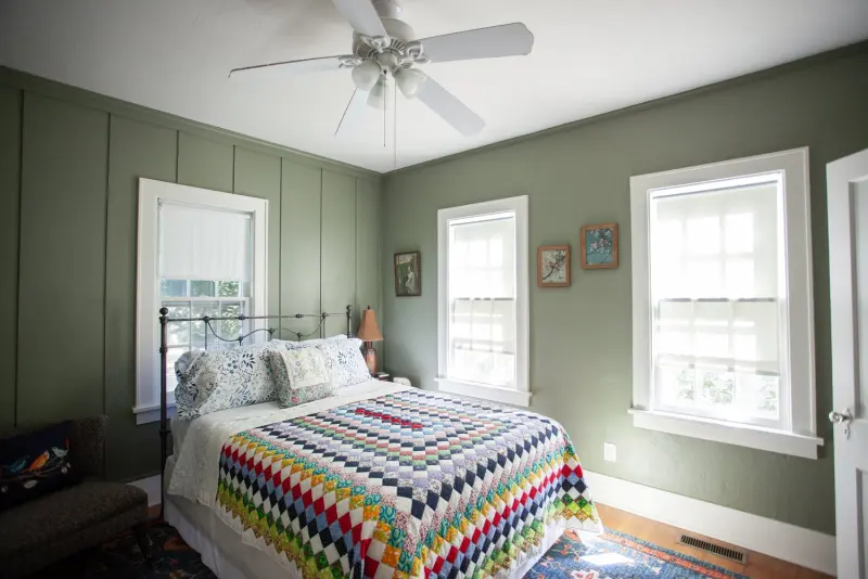 Bedroom with green panelled walls, a ceiling fan and a crocheted blanket