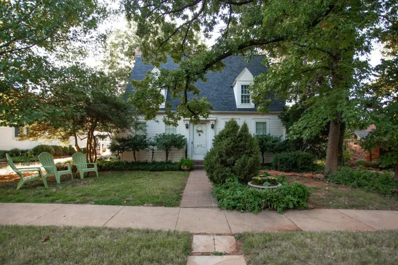 The front lawn and walk with green Adirondack chairs under the trees