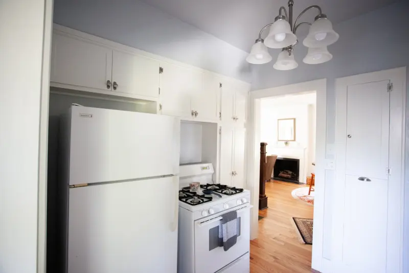Kitchen with white cabinets, a gas range and refrigerator, opening to the living room