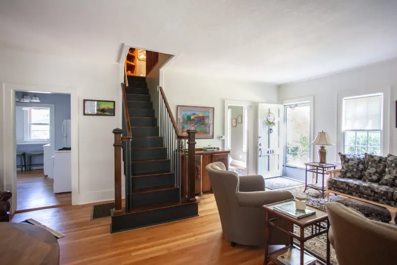 Living room with armchairs, the staircase and French doors
